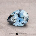 A pear-shaped blue gemstone, specifically a 1.41-carat Montana sapphire (heated), is displayed on a textured surface with the label "Earth's Treasury" at the bottom.