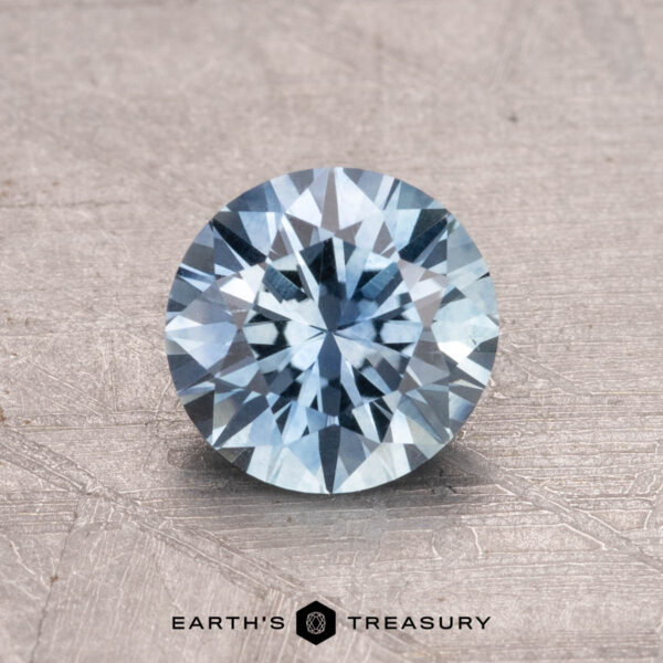 1.08-Carat Montana Sapphire (Heated) A 1.08-carat Montana sapphire, heated and featuring a faceted cut, is displayed on a textured surface.