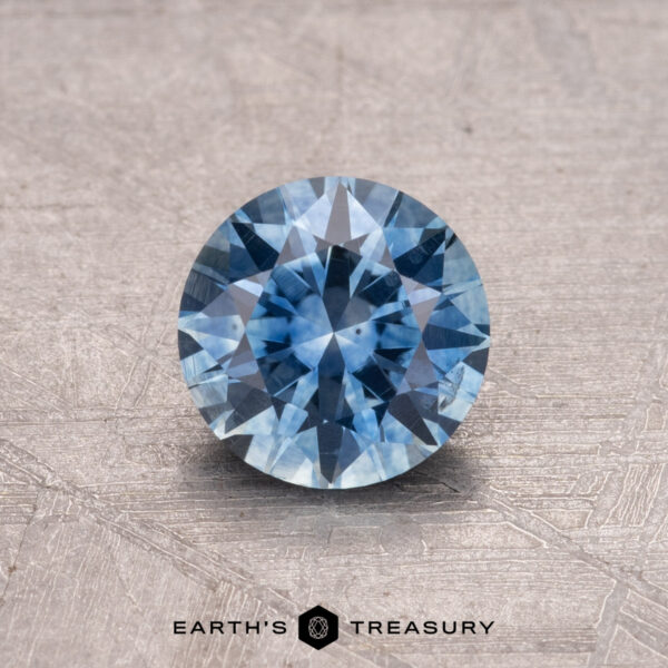 1.04-Carat Montana Sapphire (Heated) 1.04-carat Montana sapphire with a brilliant cut on a textured surface, branded "Earth's Treasury.