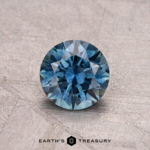 A 1.01-carat heated Montana sapphire from Earth's Treasury displayed on a textured surface.