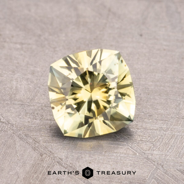 0.99-Carat Montana Sapphire (Heated) A 0.99-carat heated Montana Sapphire in a faceted cut, displayed on a textured gray surface with the text "Earth's Treasury" at the bottom.