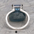 The "Lina" ring in 14k white gold, featuring a 2.34-carat Montana Sapphire, is displayed upright on a blue textured stone with the Earth's Treasury logo at the bottom.