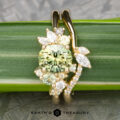 The "Liana" ring in 18k yellow gold features a 1.50-carat Australian sapphire and diamond accents, elegantly displayed on a green leaf with the Earth's Treasury logo at the bottom.
