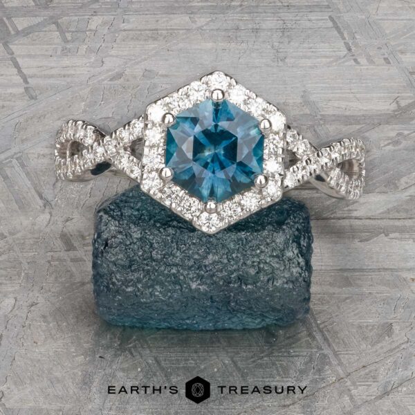 The "Graciella" ring in 14k white gold with 1.27-carat Montana sapphire The "Graciella" ring features a 1.27-carat Montana sapphire set in 14k white gold with a hexagonal diamond setting, shown on a rough blue stone.