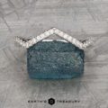 The "Graciella" band in 14k white gold, featuring a chevron-shaped design, is displayed upright on a rough blue gemstone against a textured gray background with the "Earth's Treasury" logo below.