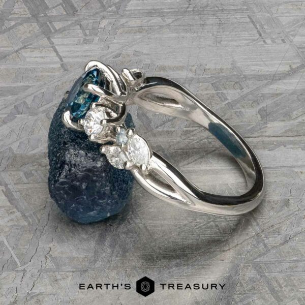 The "Lobelia" ring in platinum with 1.19-carat Montana sapphire The "Lobelia" ring in platinum, featuring a 1.19-carat Montana sapphire, is displayed on a textured gray surface with the Earth’s Treasury logo at the bottom.