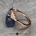The "Celeste" ring in 14k rose gold with a 2.37-carat Montana sapphire and diamond accents rests on a textured metallic surface, with "Earth's Treasury" written below.