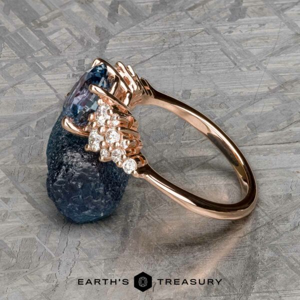 The "Celeste" ring in 14k rose gold with 2.37-carat Montana sapphire The "Celeste" ring in 14k rose gold with a 2.37-carat Montana sapphire and diamond accents rests on a textured metallic surface, with "Earth's Treasury" written below.