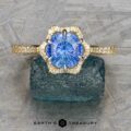 The "Plumeria" ring in 18k yellow and platinum features a 1.18-carat Ceylon sapphire surrounded by diamonds, displayed on dark stone with the "EARTH'S TREASURY" logo below.