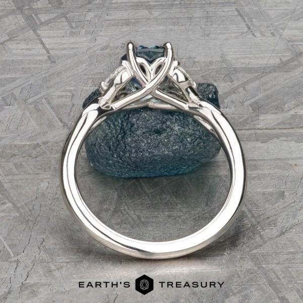 The "Anise" ring in platinum with 1.37-Carat Montana Sapphire The "Anise" ring in platinum features a 1.37-carat Montana Sapphire in an intricate setting, displayed upright on a rough blue stone with the Earth's Treasury logo below.