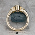 The "Kaelin" Ring in 14k yellow gold with a 1.00-carat Ceylon sapphire is shown upright in a prong setting on a dark stone background, viewed from the side. The "Earth's Treasury" logo appears at the bottom.