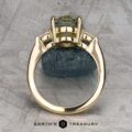 The "Dryad" ring in 14k yellow gold with a 3.50-carat Montana sapphire is displayed upright on a stone, with the Earth's Treasury logo at the bottom.