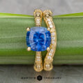 The "Marilyn" ring in 18k yellow gold with a 3.20-carat Ceylon sapphire is paired with the "Marilyn" band in 18k yellow gold, both displayed on a green stem with Earth's Treasury branding below.