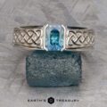 The "Shannon" ring in platinum, featuring a 1.06-carat Montana sapphire and Celtic knot designs, is shown on a rough blue-green stone with the EARTH'S TREASURY logo below.