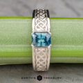 The "Shannon" ring in platinum, featuring a 1.06-carat Montana sapphire and detailed Celtic knotwork, is shown on a green stem with "Earth's Treasury" beneath.