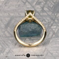 The "Antoinette" ring in 14k yellow gold with a 1.69-carat Australian sapphire stands upright before a rough blue mineral, with small diamonds and a geometric metallic background. "Earth's Treasury" appears at the bottom.
