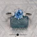The "Clary" ring in 14K white gold with a 1.72-carat Montana sapphire is displayed on a rough blue crystal, with "EARTH'S TREASURY" text below.