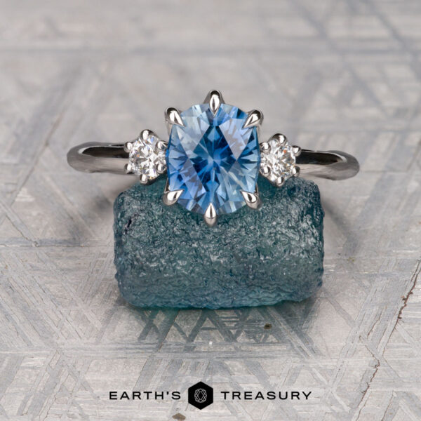 The "Clary" ring in 14K white gold with 1.72-carat Montana sapphire The "Clary" ring in 14K white gold with a 1.72-carat Montana sapphire is displayed on a rough blue crystal, with "EARTH'S TREASURY" text below.