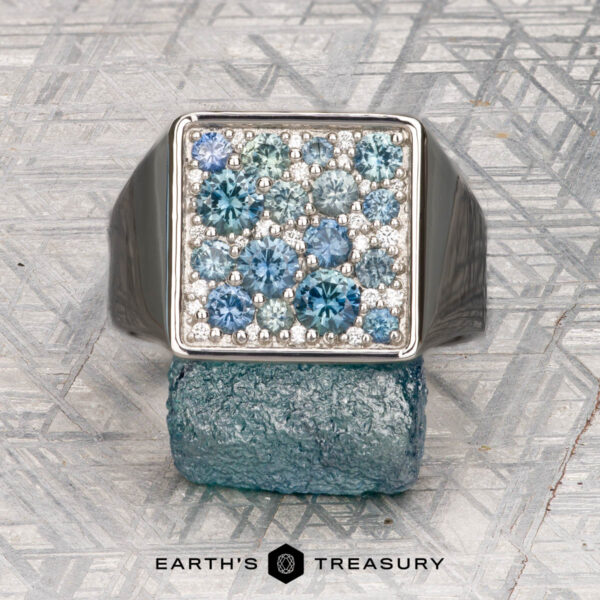 The "Whitaker" ring in platinum The "Whitaker" ring in platinum features a square face set with blue gemstones, shown on a rough blue mineral with "Earth's Treasury" below.