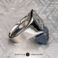 The "Whitaker" ring in platinum features a square face set with blue gemstones, shown on a rough blue mineral with "Earth's Treasury" below.