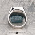 The "Whitaker" ring in platinum features a square face set with blue gemstones, shown on a rough blue mineral with "Earth's Treasury" below.