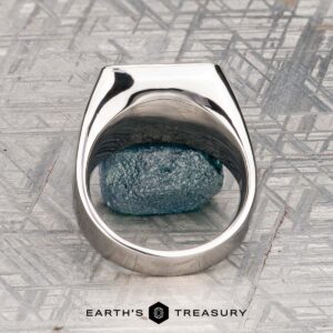 The "Whitaker" ring in platinum features a square face set with blue gemstones, shown on a rough blue mineral with "Earth's Treasury" below.
