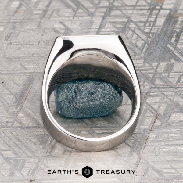 The "Whitaker" ring in platinum The "Whitaker" ring in platinum features a square face set with blue gemstones, shown on a rough blue mineral with "Earth's Treasury" below.
