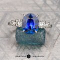 The "Celosia" ring in platinum features a 2.75-carat Madagascar sapphire and diamond accents, elegantly displayed on rough blue celosia crystal atop a patterned surface.