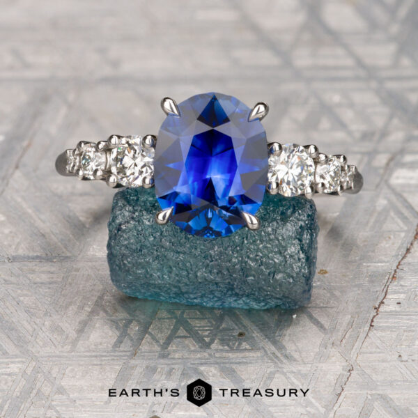 The "Celosia" ring in platinum with 2.75-carat Madagascar sapphire The "Celosia" ring in platinum features a 2.75-carat Madagascar sapphire and diamond accents, elegantly displayed on rough blue celosia crystal atop a patterned surface.