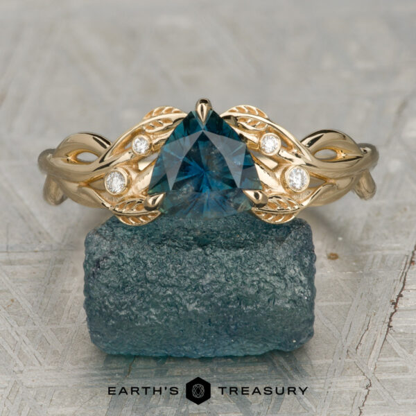 The "Viney" ring in 14K yellow gold with 1.39-carat Montana sapphire The "Viney" ring in 14K yellow gold features a 1.39-carat Montana sapphire and four small round diamonds, showcased on a textured blue stone.