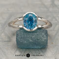 The "Madi" ring in 14K white gold with a 1.62-carat Montana sapphire is showcased on a rough blue stone, with the "Earth's Treasury" logo and text at the bottom.