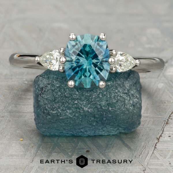 Stacked from 15 images. Method=B (R=7,S=2) The Nymph Ring with two side diamonds is displayed on a rough blue gem, with "Earth's Treasury" and a logo visible at the bottom.