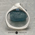A platinum “Winona” ring with a 1.21-carat Montana sapphire rests on a textured blue stone, displayed on a patterned surface with the text "Earth's Treasury" below.