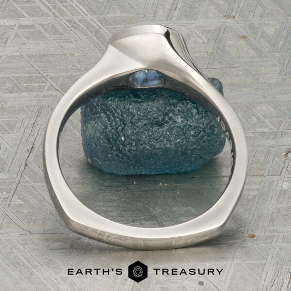 The “Winona” ring in platinum with 1.21-carat Montana sapphire A platinum “Winona” ring with a 1.21-carat Montana sapphire rests on a textured blue stone, displayed on a patterned surface with the text "Earth's Treasury" below.