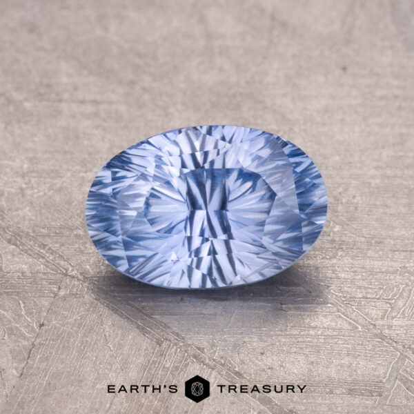 1.30-Carat Ceylon Sapphire A 1.30-Carat Ceylon Sapphire, a faceted blue gem, is showcased on a textured background with the "Earth's Treasury" logo beneath.