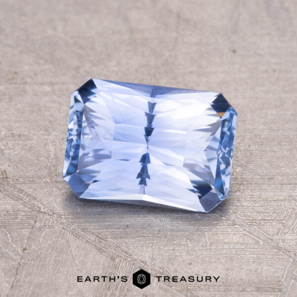 1.42-Carat Ceylon Sapphire A 1.42-carat Ceylon sapphire, rectangular with faceted cuts, rests on a textured gray surface marked "Earth's Treasury.