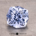 3.05-Carat Ceylon Sapphire, a faceted gemstone with a hexagonal shape on a textured surface. Text reads "Earth's Treasury" below.