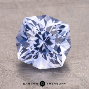 3.05-Carat Ceylon Sapphire, a faceted gemstone with a hexagonal shape on a textured surface. Text reads "Earth's Treasury" below.
