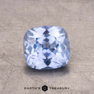 A 1.28-carat Ceylon Sapphire, cushion-cut and reflecting light beautifully, rests on a textured surface. Below, the text reads "Earth's Treasury.
