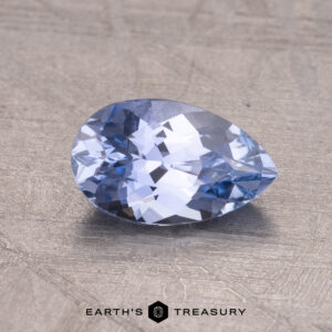 A 1.09-carat Ceylon sapphire, pear-shaped and faceted, on a textured surface.