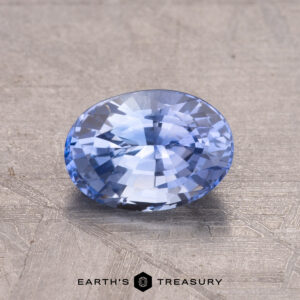 A 1.45-carat Ceylon sapphire, heat-treated, rests on a textured surface.