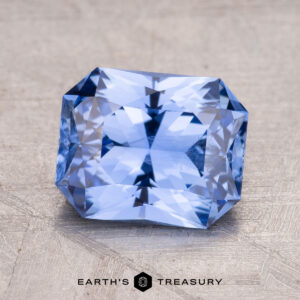 A 2.68-carat Ceylon Sapphire, with complex facets and a sparkling blue hue, rests on a textured surface.