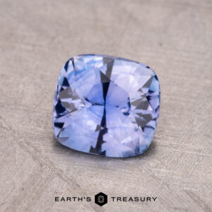A stunning 1.45-carat Ceylon sapphire, cushion-cut to perfection, rests elegantly on a textured surface.