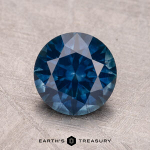 A 2.07-carat Montana sapphire (heated) sits on a textured surface, with "Earth's Treasury" below.