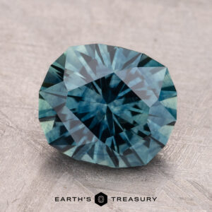 A 3.35-carat heated Montana sapphire gemstone, shown against a textured background, is labeled "Earth's Treasury" in the corner.