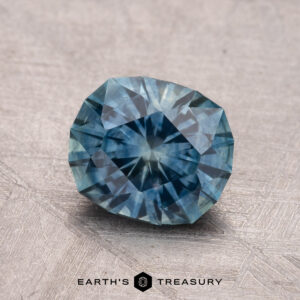 A 1.72-carat heated Montana sapphire with intricate facets displayed against a textured surface.