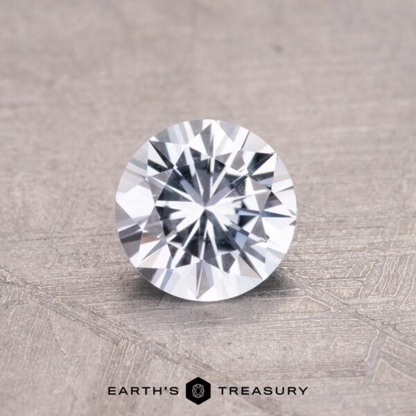 0.66-Carat Montana Sapphire A 0.66-carat Montana sapphire with intricate facets rests on a textured gray surface.
