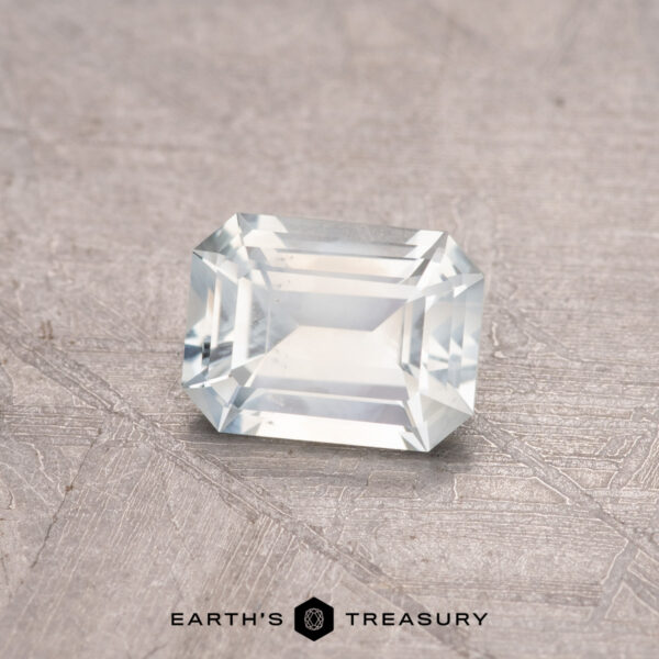 0.82-Carat Montana Sapphire A rectangular, faceted white gemstone on a textured gray surface with "0.82-Carat Montana Sapphire" written below.