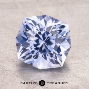 3.05-Carat Ceylon Sapphire, a faceted gemstone with a hexagonal shape on a textured surface. Text reads "Earth's Treasury" below.