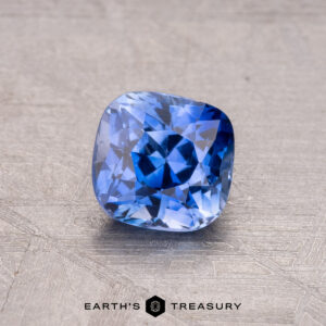 Cushion-cut 1.10-Carat Ceylon Sapphire (Heated) on a textured surface, with "Earth's Treasury" below.